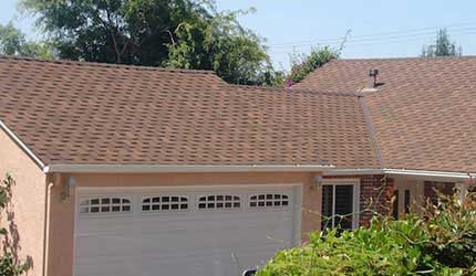 Peach colored home with white garage door and brown composition shingle roof